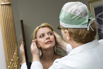 a surgeon examining a mature woman's face