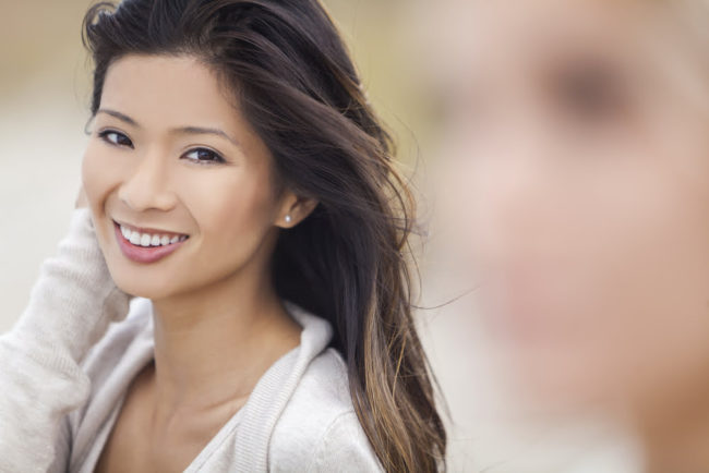 a smiling, happy asian woman with smooth even skin.