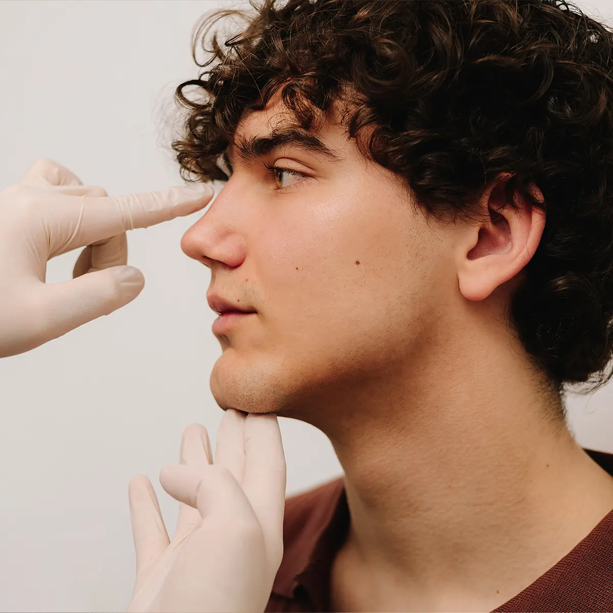 plastic surgeon examining patient's nose for rhinoplasty